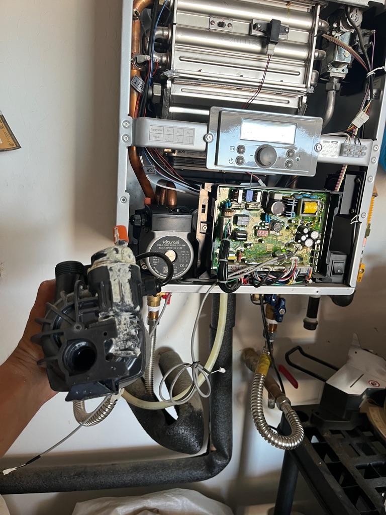 Close-up of failed recirculation pump and leaking mixing valve removed during tankless water heater repair in Las Vegas
